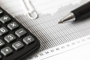 Kalkulator finansowy leżący obok wykresu i dokumentów z długopisem