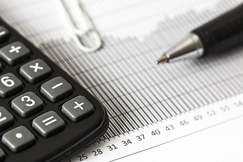 Kalkulator finansowy leżący obok wykresu i dokumentów z długopisem