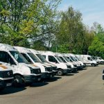 Rząd białych busów dostawczych zaparkowanych na firmowym placu