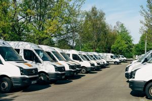 Rząd białych busów dostawczych zaparkowanych na firmowym placu